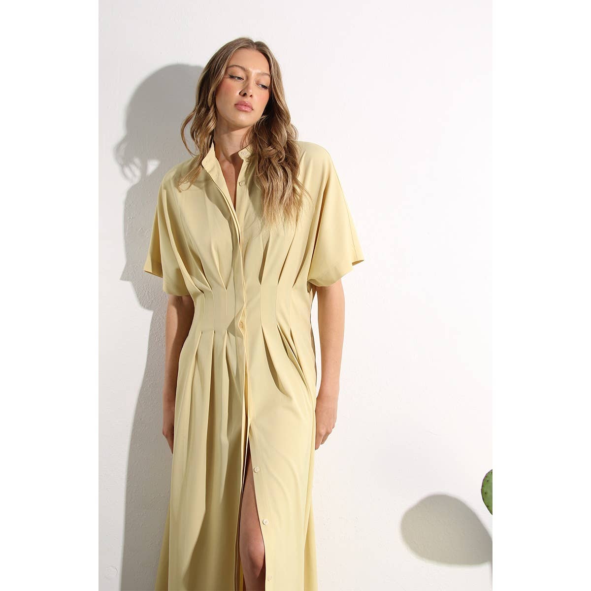 Lifestyle photo of North and Five's butter-yellow button-down dress. Styled next to plant