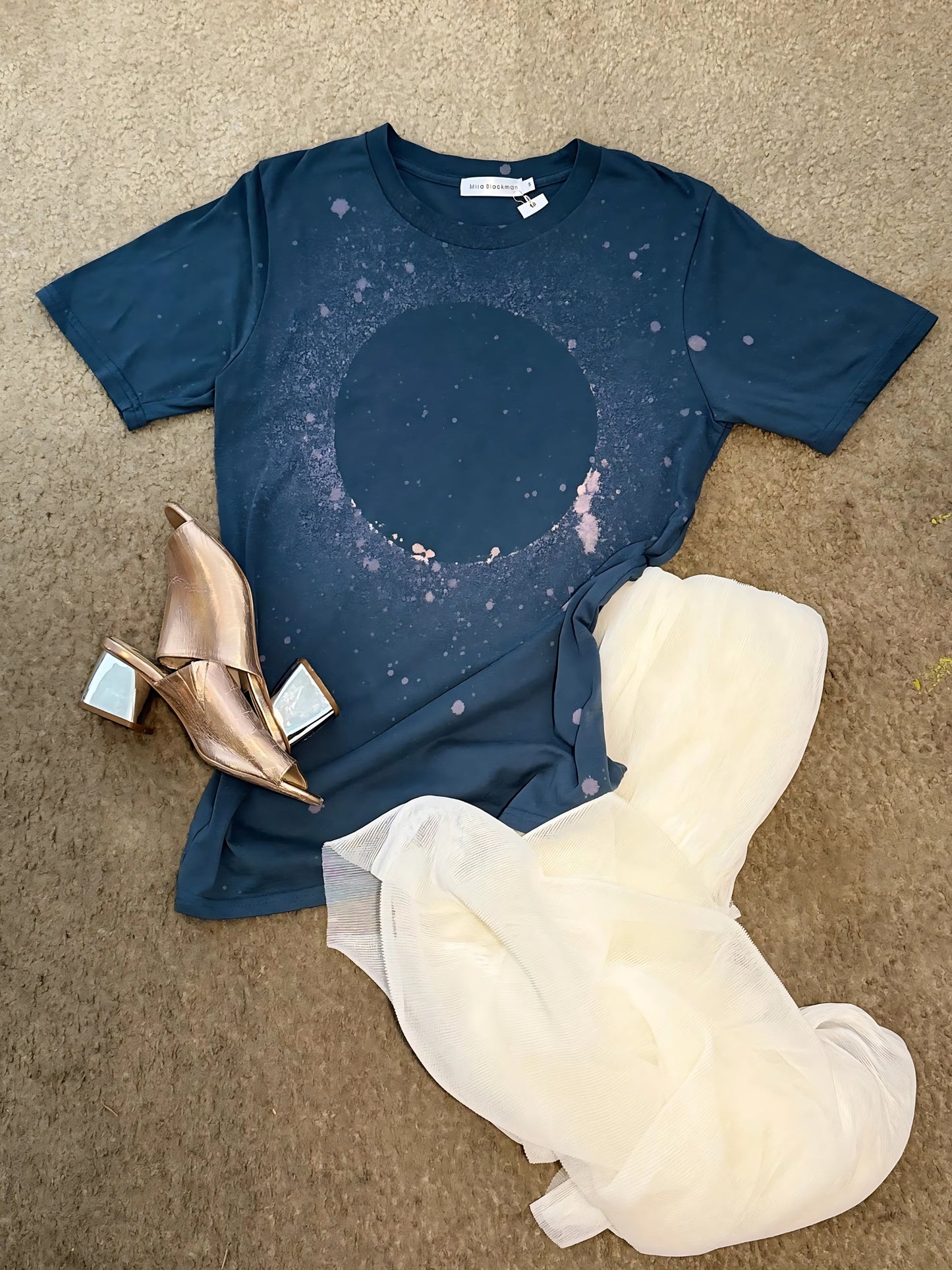 Flat lay of Luminary Organic Tee by Mira Blackman – Slate. Styled with white chiffon skirt and metallic pink mules.