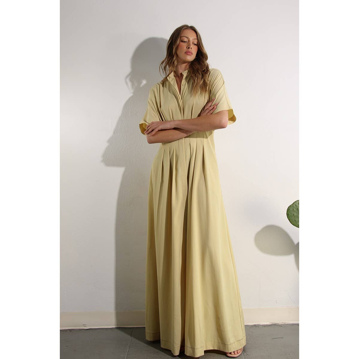 Full length lifestyle photo of Butter Yellow Long Button-Down Dress. Elegantly styled with plotted plant.