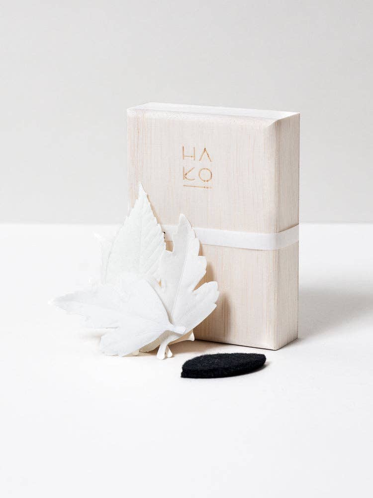 Japanese HA KO paper incense leaves in a wooden box, arranged on white table and neutral background.