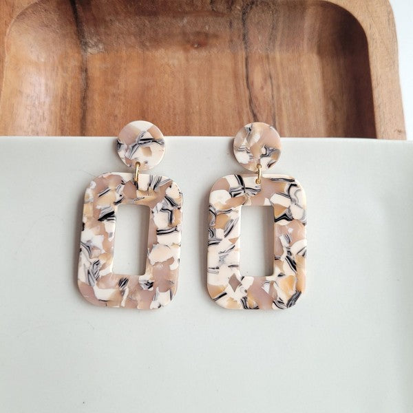 Modern sculptural sandstone-toned acrylic earrings with stainless steel posts, shown on white table.
