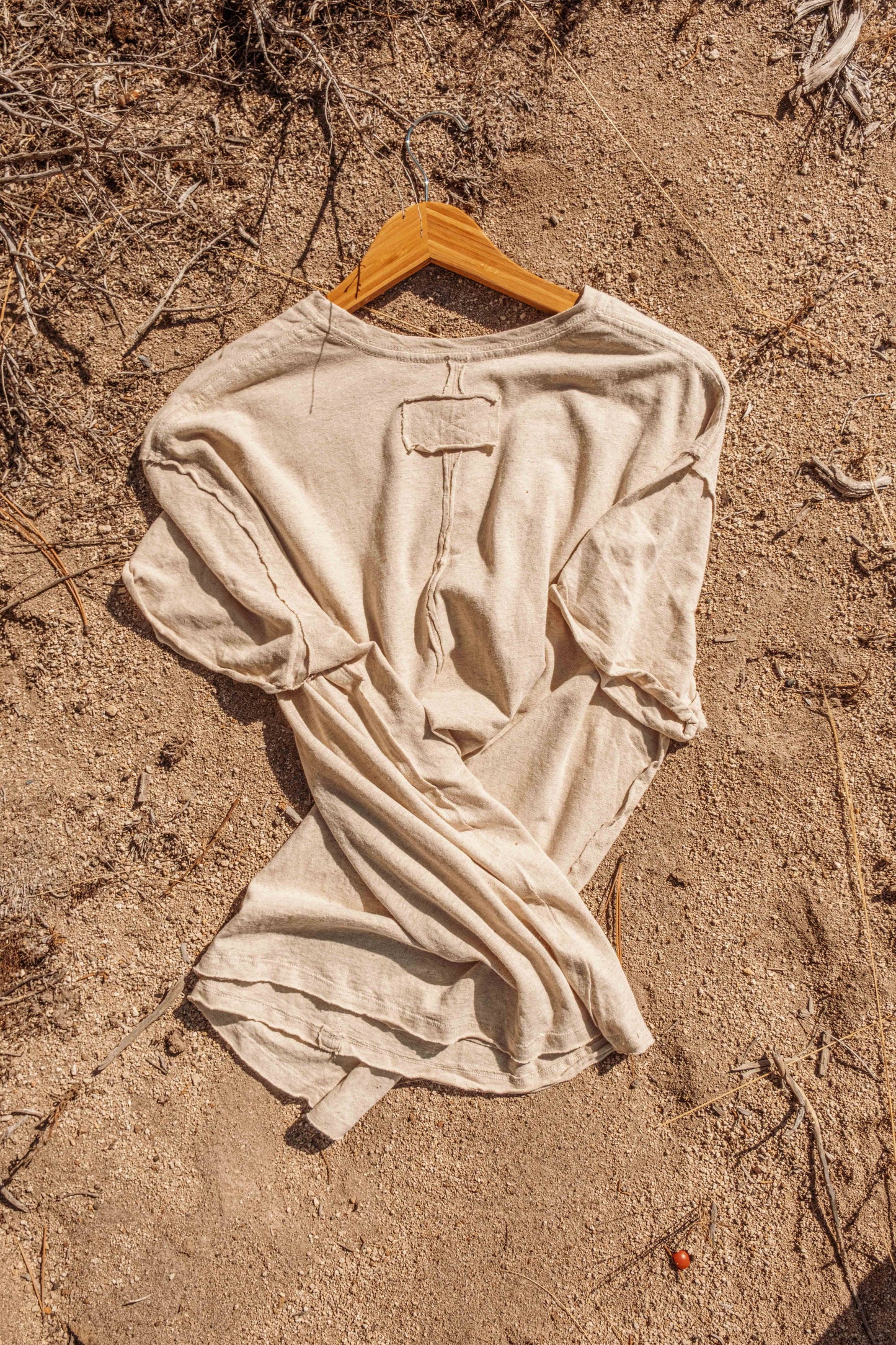 Flat lay of back of Hemp Organic Cotton Unisex T-Shirt on ground, outside in earth.