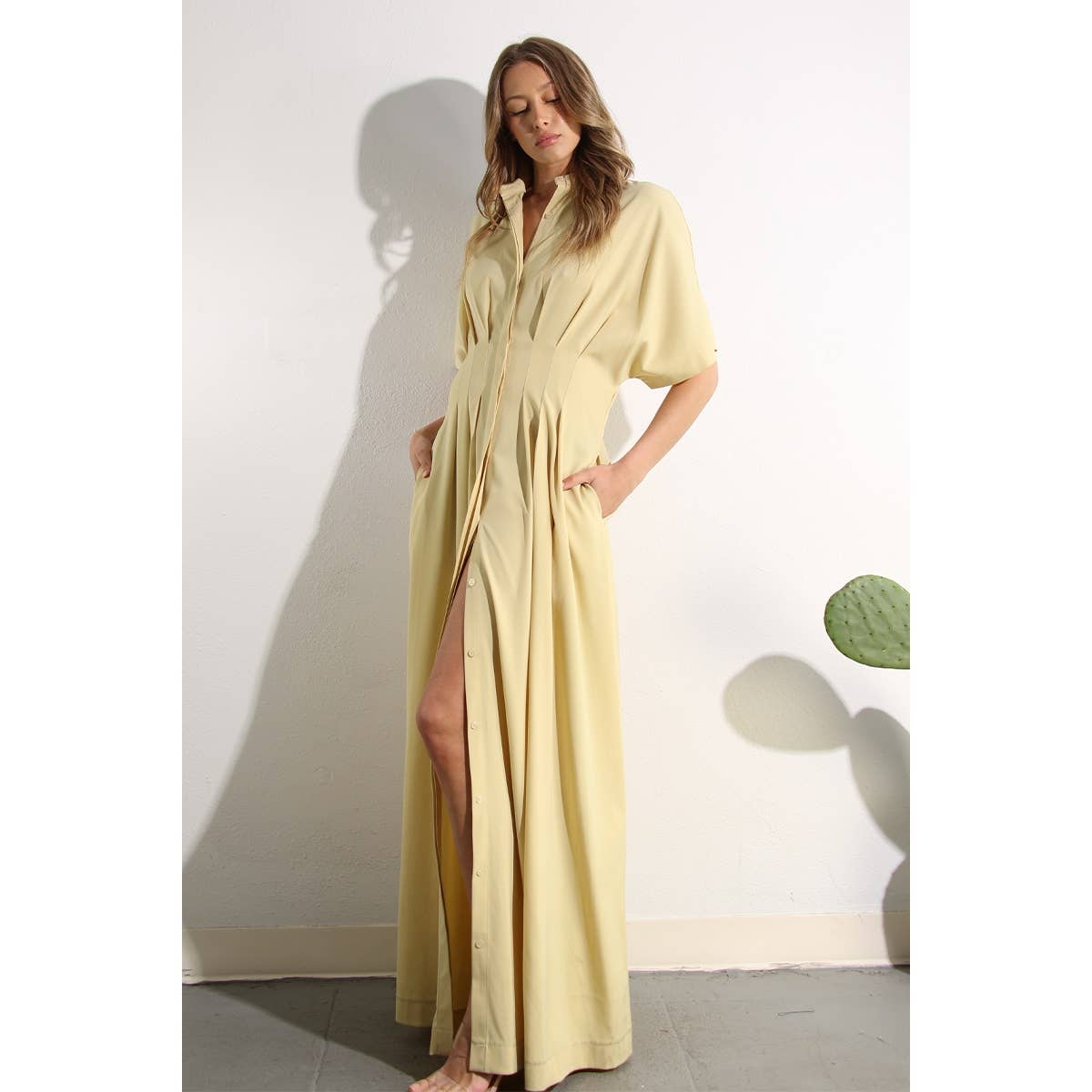 Lifestyle photo of North and Five's Butter Yellow Long Button-Down Dress. Model showcasing pockets and leg slit.