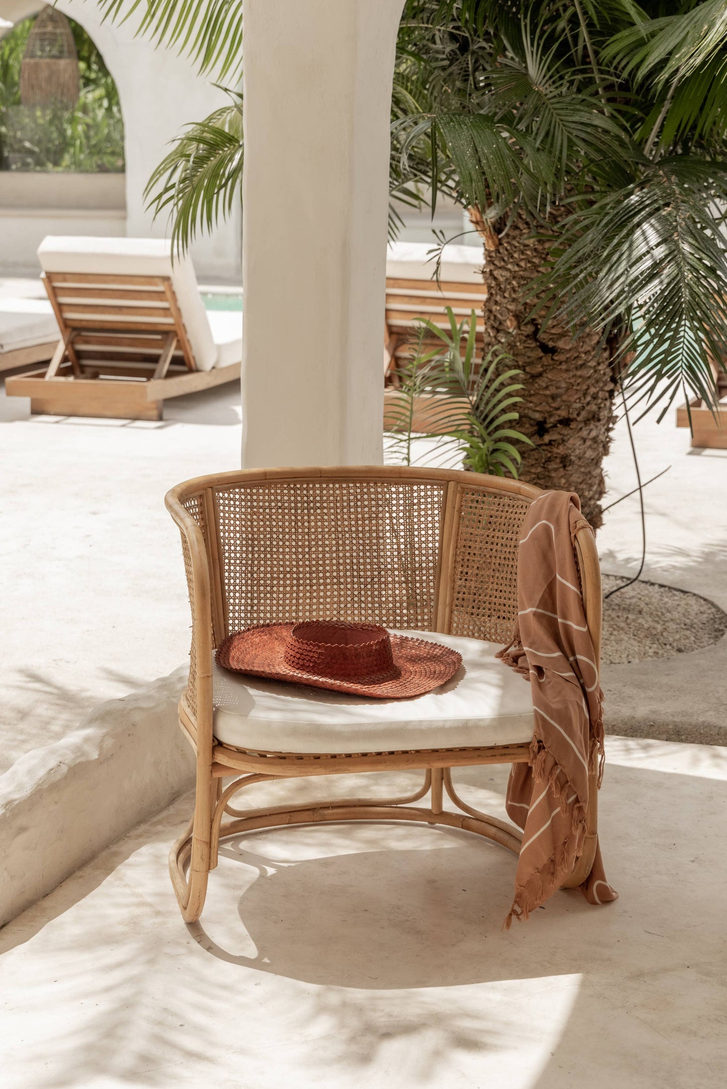 Papale Sun Hat in Clay, photographed on wicker beach chair.