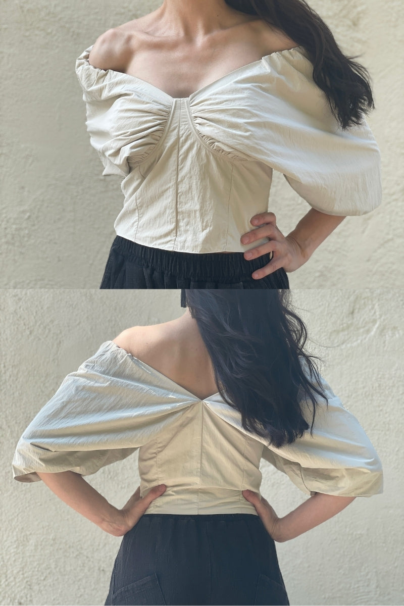 Front and back view of Woman wearing an off-shoulder beige top against a plain background.