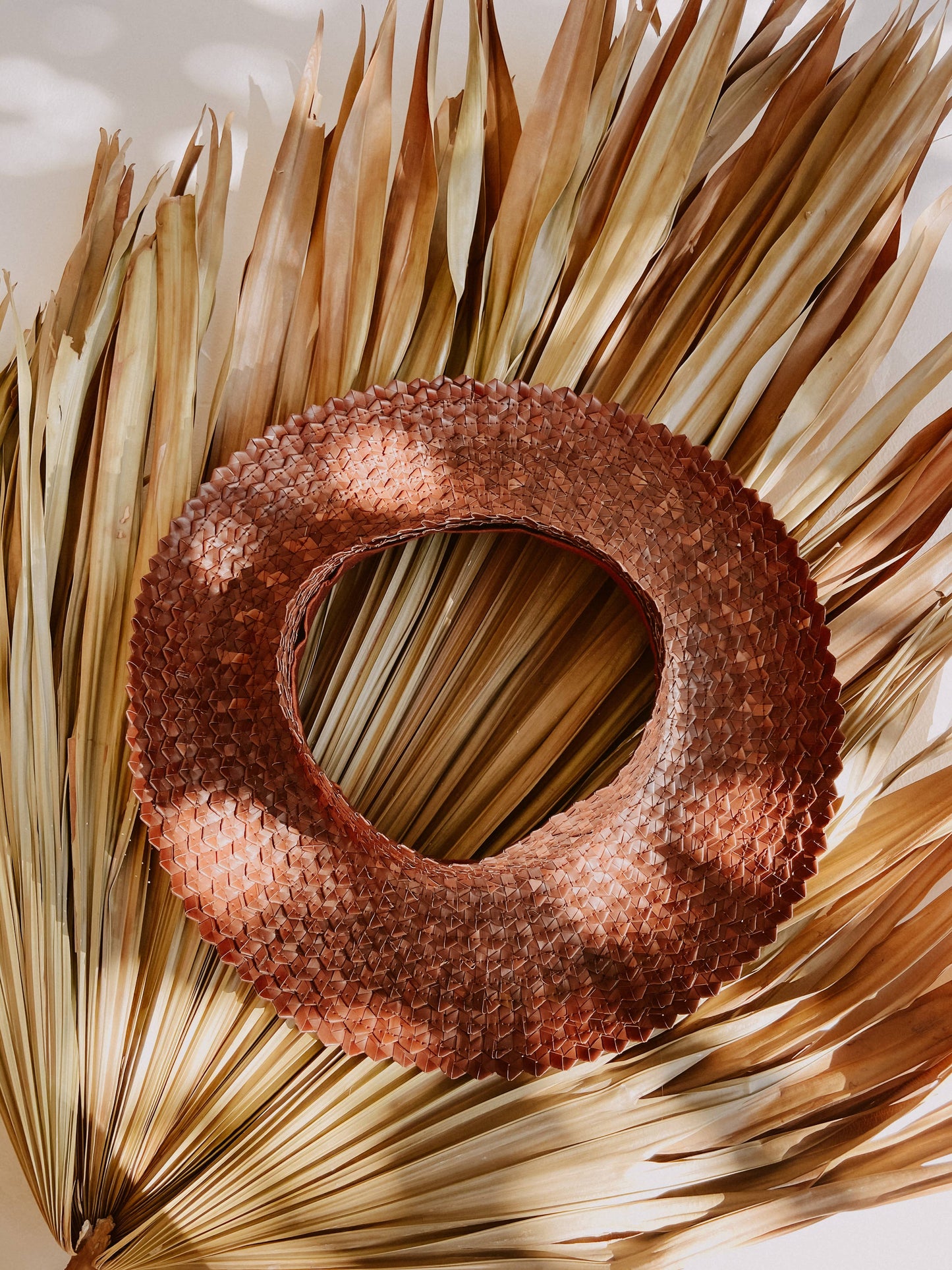 Birdseye view of Papale Sun Hat in Clay, resting on leaf in sunshine. 