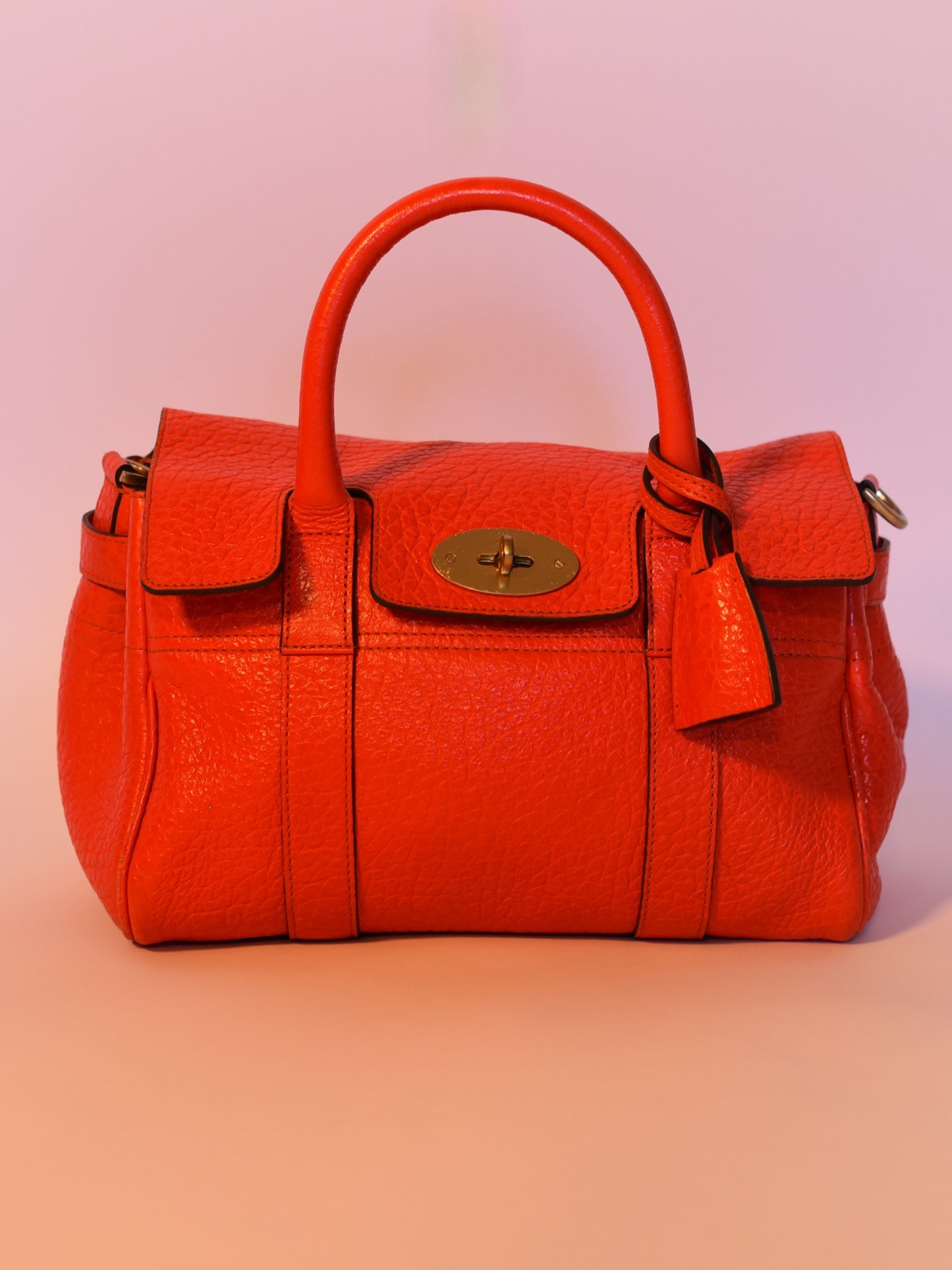 Close up of Coral orange Mulberry Bayswater leather bag with Postman’s Lock, top handles, and brass hardware