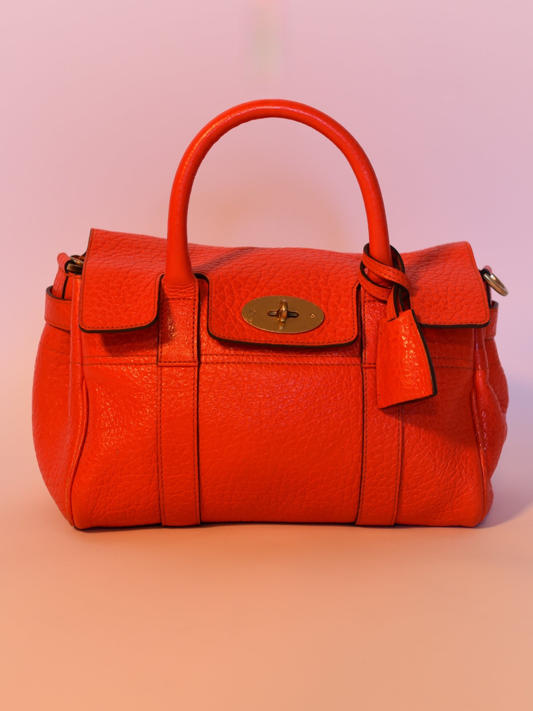 Close up of Coral orange Mulberry Bayswater leather bag with Postman’s Lock, top handles, and brass hardware