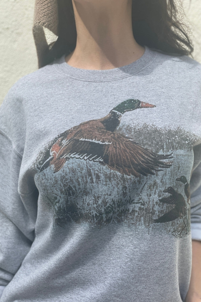 Close up of Gray sweatshirt with a vintage-duck-graphic-worn by a woman.