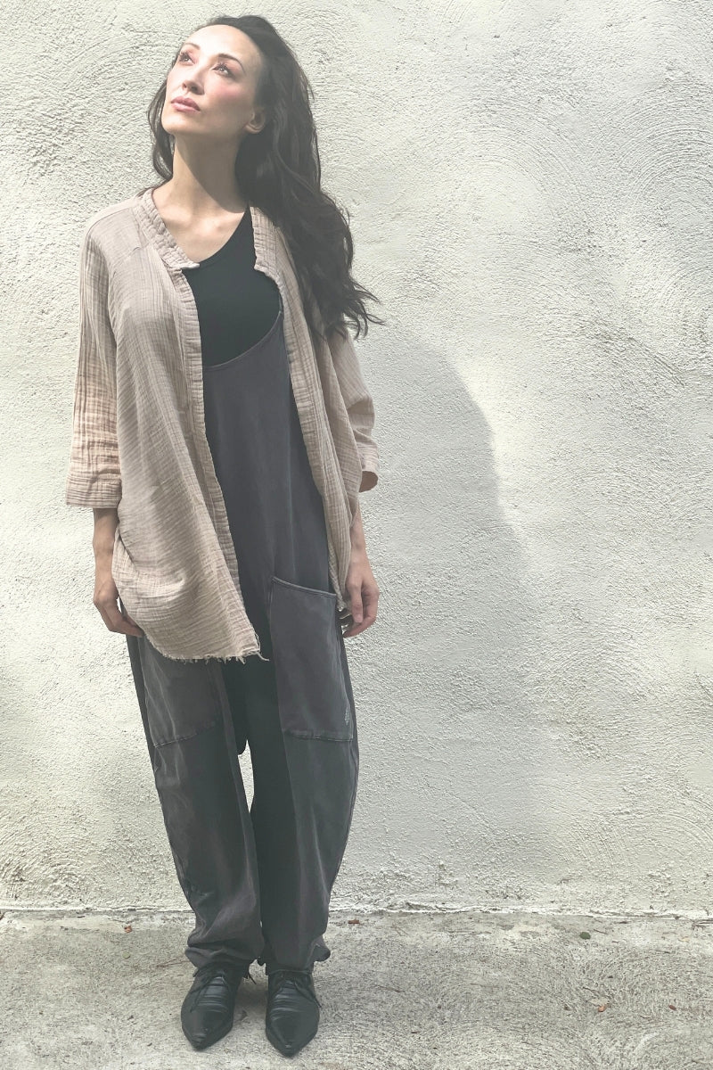 Model wearing a beige kimono over a black t-shirt and jumpsuit against a plain wall.