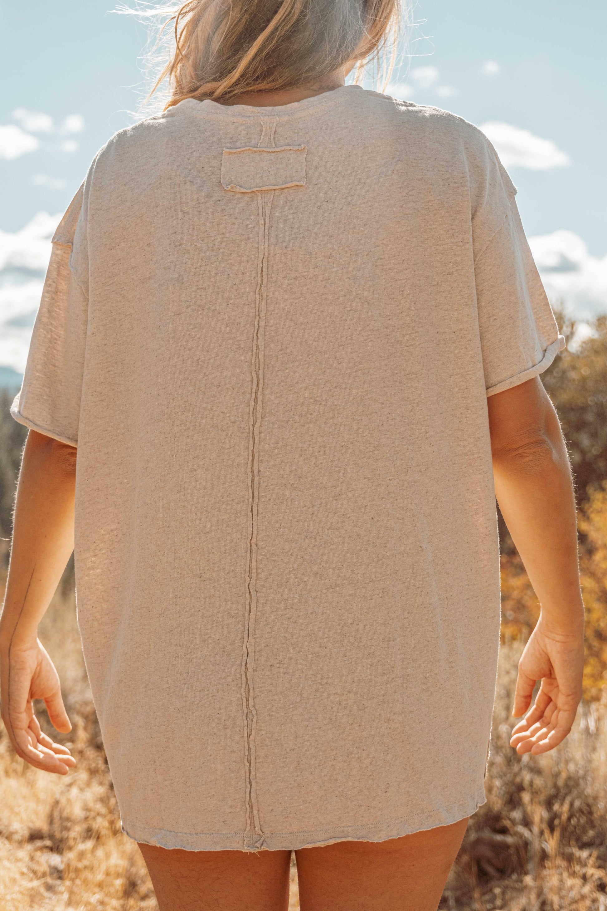 Full back view of Hemp Organic Cotton Unisex T-Shirt. Model's long blonde hair swept to side.