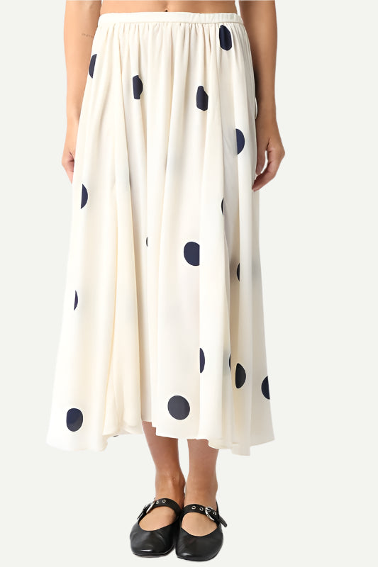 Black-and-white polka dot midi skirt with asymmetrical hem, styled for a modern boho look