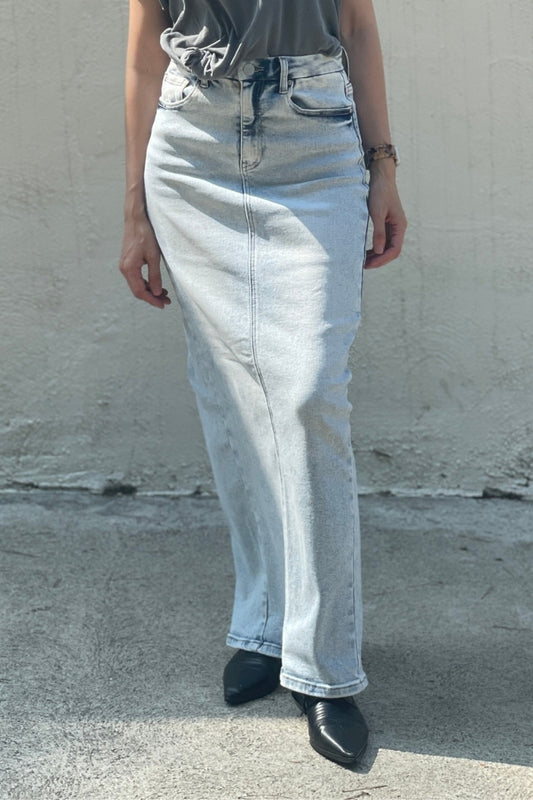 Model wearing light blue denim maxi skirt, black tee-shirt and black shoes against a plain background.