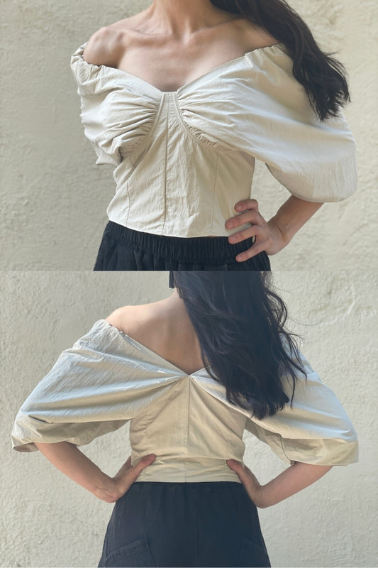Front and back view of Woman wearing an off-shoulder beige top against a plain background.