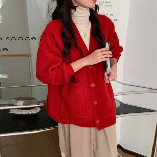 Oversized red cardigan with deep V-neck and soft knit texture, layered over beige outfit.